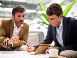 Two business professionals discussing documents, representing a consultation with a real estate consultant in Gurgaon at a modern office.