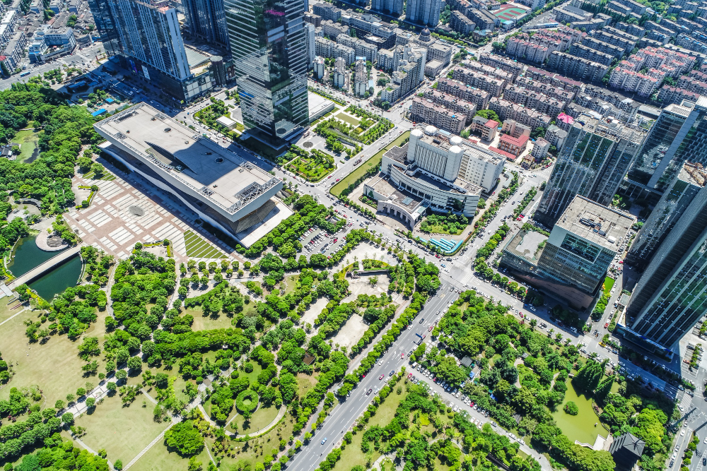 Aerial view of a bustling urban area in Gurgaon featuring SCO plots, showcasing modern commercial buildings and lush greenery.