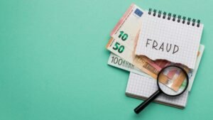 Notebook with 'Fraud' written on it, placed on euro bills with a magnifying glass, symbolizing property fraud investigation.